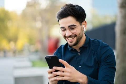 Young man using his mobile phone outdoors. Stock Photos