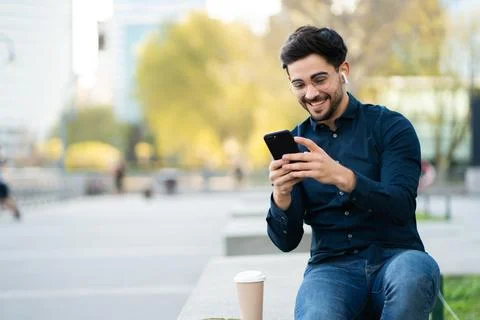Young man using his mobile phone outdoors. Stock Photos