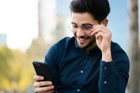 Young man using his mobile phone outdoors. Stock Photos