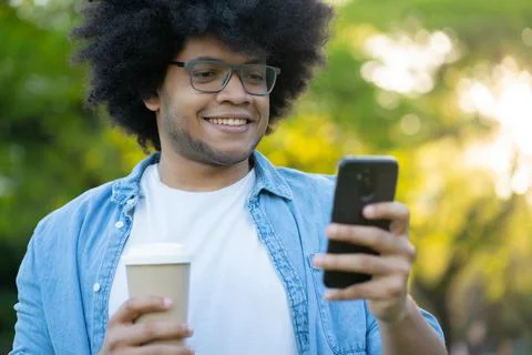 Young man using his mobile phone outdoors. Stock Photos