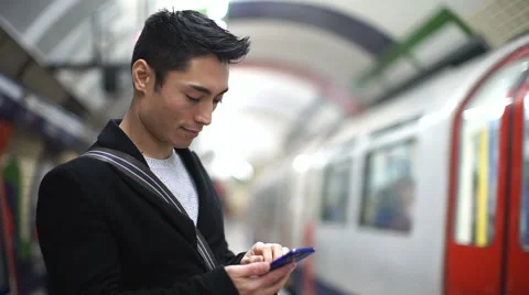 Young man using his phone as a metro train arrives Stock Footage 46952071