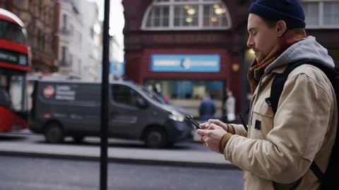 Young man using his phone as he walks on the high street, in slow motion Stock-Footage 84673385