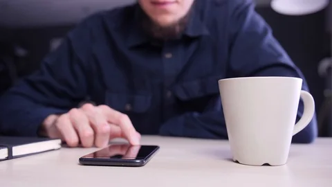 Young man using his phone, drinking coffee or tea and checking social networks Stock Footage 124215923