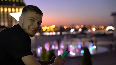 Young man using his smartphone and smiling with greenscreen chromakey on Stock Footage 117629157