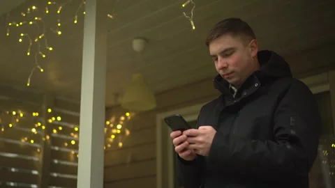 A young man is using his smartphone outdoors in a charming atmosphere adorned Stock Footage 303439809