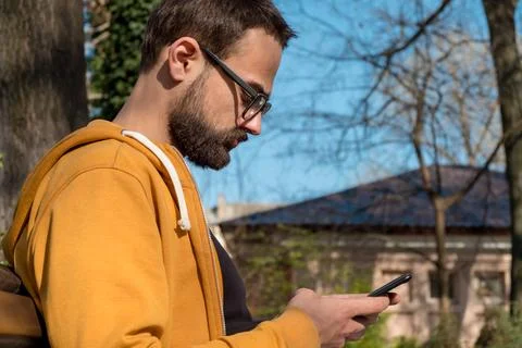 Young Man Using His Smartphone and Laptop Outdoors Stock Photos