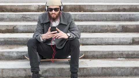Young man using his smartphone for listening to music. Stock Photos