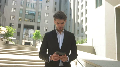 Young man using his tablet in front of a business center Stock Footage 68598429
