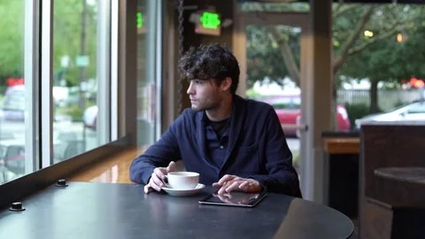 Young man using his tablet while drinking coffee in a cafe 스톡 동영상 83392773