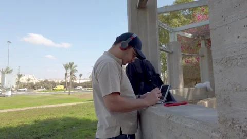 Young man using his tablet in a park on a sunny day. Stock Footage 324927092