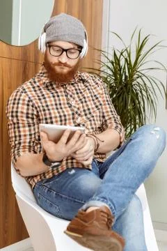 Young man using his tablet while sitting on chair Stock Photos