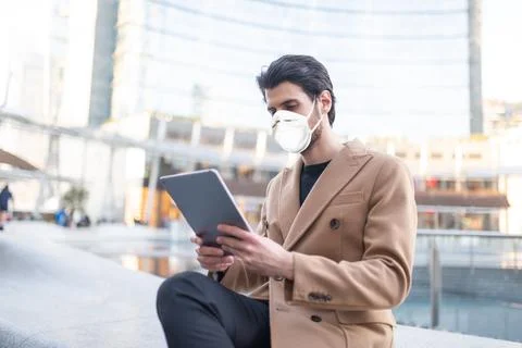 Young man using his tablet outdoor while wearing a mask Stock Photos