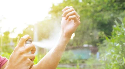 Young man using insect repellent against some kind of insects, healthcare 库存照片