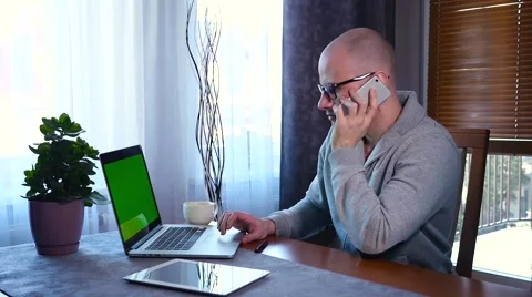 Young man is using laptop and talking on the phone. Green screen. Stock Footage 61281483