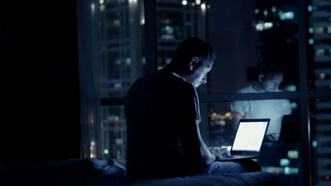 Young man using laptop and falling asleep on bed at night at home Stock Footage 83310250