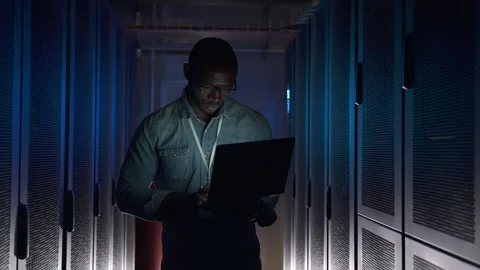 Young man using laptop and walking in dark interior while working at office Stock Footage 160805389