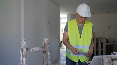 Young man using laptop and verifying papers on part time job in construction Video stock 222755544