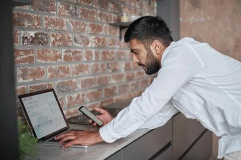 Young man using a laptop and a smartphone at the same time. Stock Photos