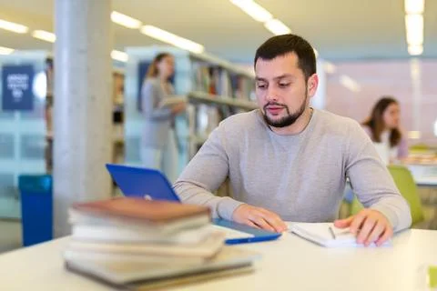 Young man using laptop and books for research in library Foto stock