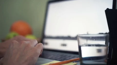 Young man using laptop in cafe. Glass of water, notepad and pencil on table Stock Footage 82936522