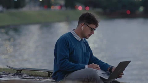 Young Man Using Laptop in City Park by the River Stock Footage 237055379