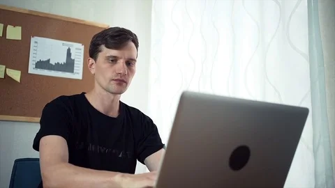 Young man using laptop computer in the home office Stock Footage 79896370