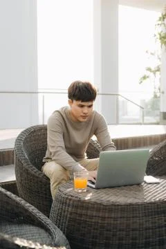 A young man using laptop computer while sitting on a sofa outside Stock Photos