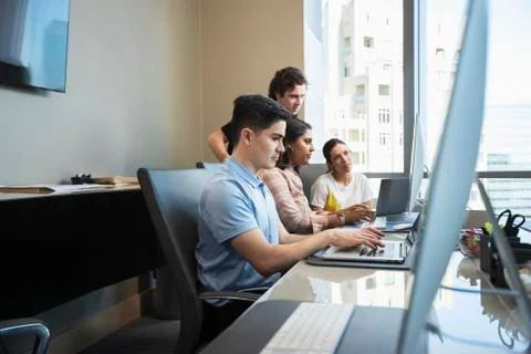 Young man using laptop computer in office conference room, co-workers having 库存照片