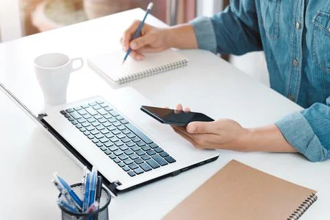 Young man using laptop computer and mobile phone When looking for financial i Stock Photos