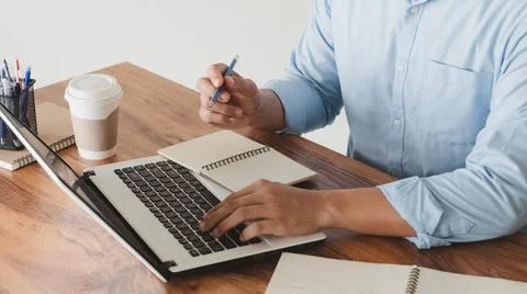 Young man using laptop computer and mobile phone When looking for financial i Stock Photos