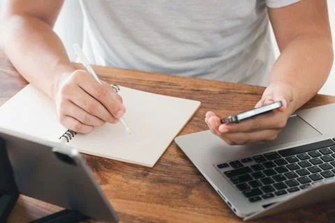 Young man using laptop computer and mobile phone When looking for financial i Stock Photos