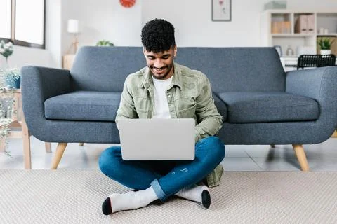 Young man using laptop computer relaxing at home. Stock Photos