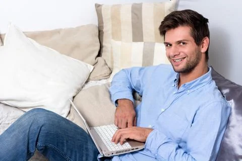 Young man using laptop on couch Stock Photos