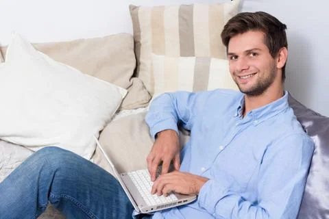 Young man using laptop on couch Foto stock