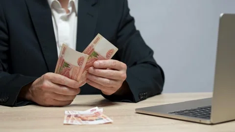 Young man using laptop counting ruble money at table. Stock Footage 252368323