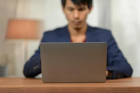 Young Man Using Laptop at Desk in a Bright Modern Indoor Space Stock Photos