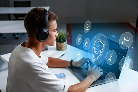 Young man using laptop with digital security interface in modern office setting Stock Photos