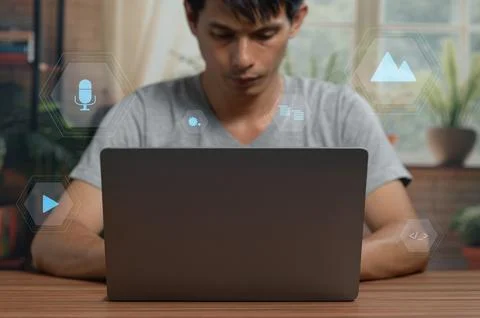 Young Man Using Laptop with Digital Technology Icons in Modern Indoor Setting Stock Photos