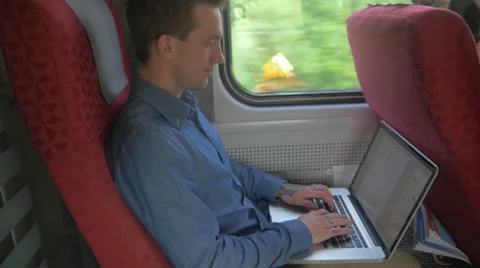 Young man using a laptop to do work on a train Stockbeeldmateriaal 51832721