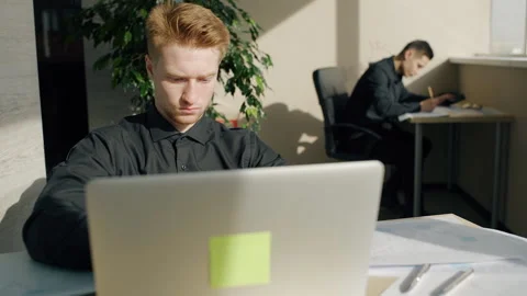 Young man is using laptop during working day in modern office. Stock Footage 90365824