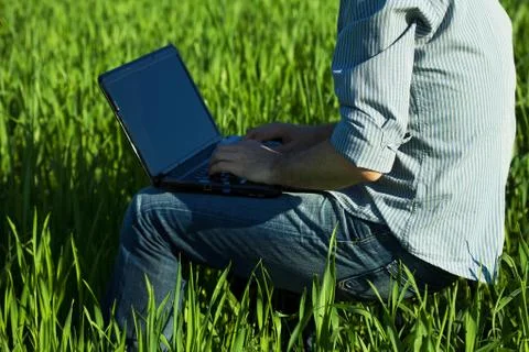 Young man using laptop in the field Stock Photos