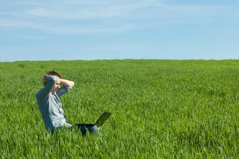Young man using laptop in the field Stock Photos