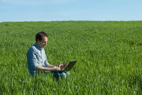 Young man using laptop in the field Stock Photos