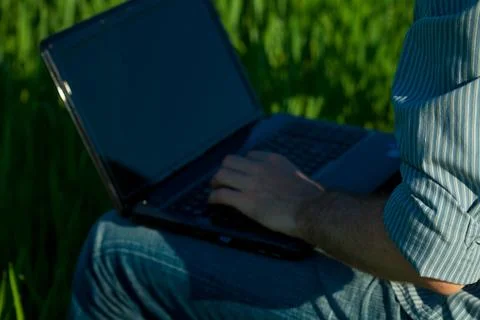 Young man using laptop in the field Stock Photos