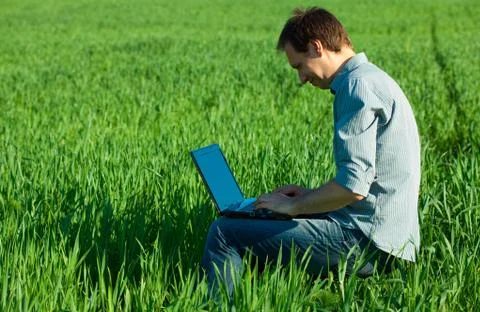 Young man using laptop in the field Stock-Fotos