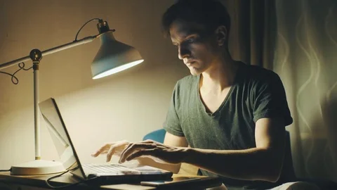 Young man using laptop having video call making notes in a notebook at home Stock Footage 78766887
