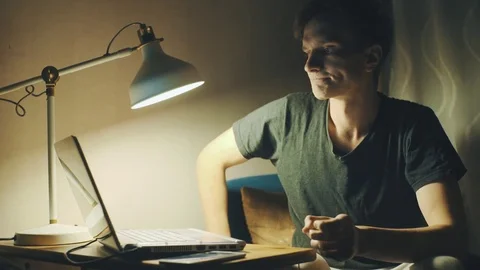 Young man using laptop having video call at home in the evening Stock Footage 78766970