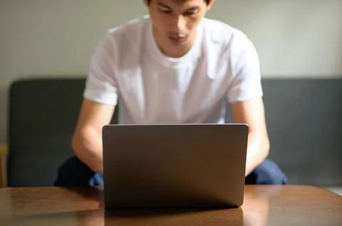 Young Man Using Laptop at Home, Focused on Work or Study Foto stock
