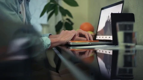 Young man using laptop in kitchen. Glass of water, notepad and pencil on table Stock Footage 82936839