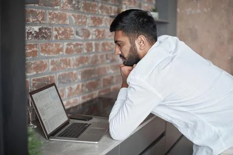 Young man using a laptop in the kitchen. Stock Photos
